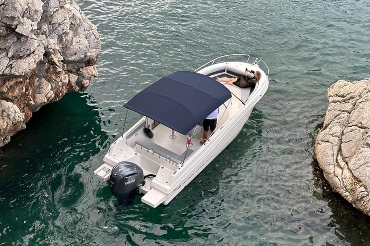 um barco branco na água ao lado de algumas pedras