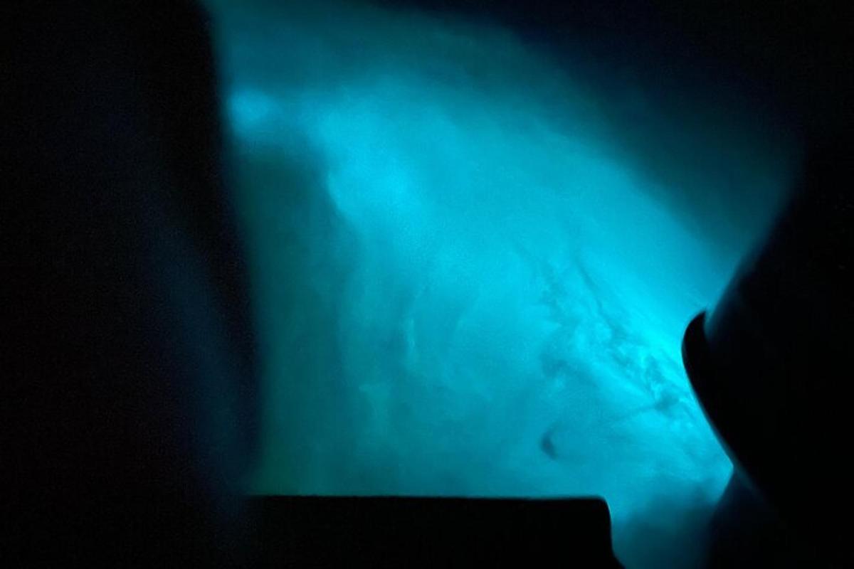 o persoană care stă în întuneric cu o lumină albastră