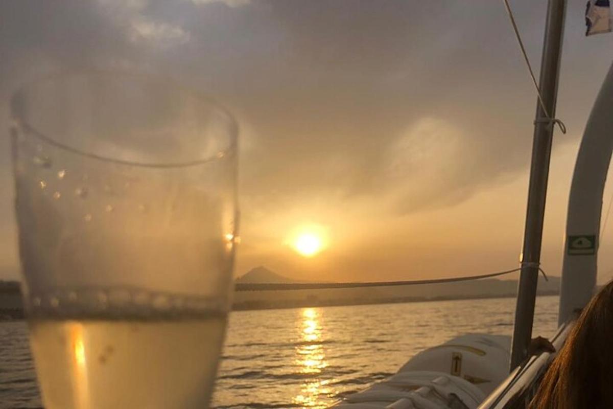 a glass of wine sitting on a boat with the sunset