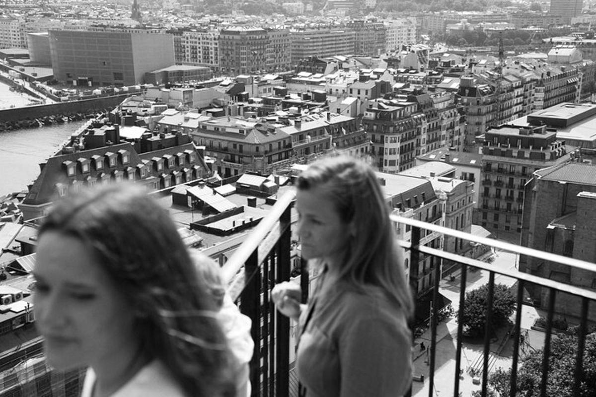 Dos mujeres caminando por un balcón con vistas a una ciudad.
