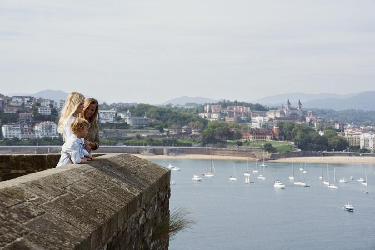Una mujer y un niño sentados en un muro con vistas a un puerto.