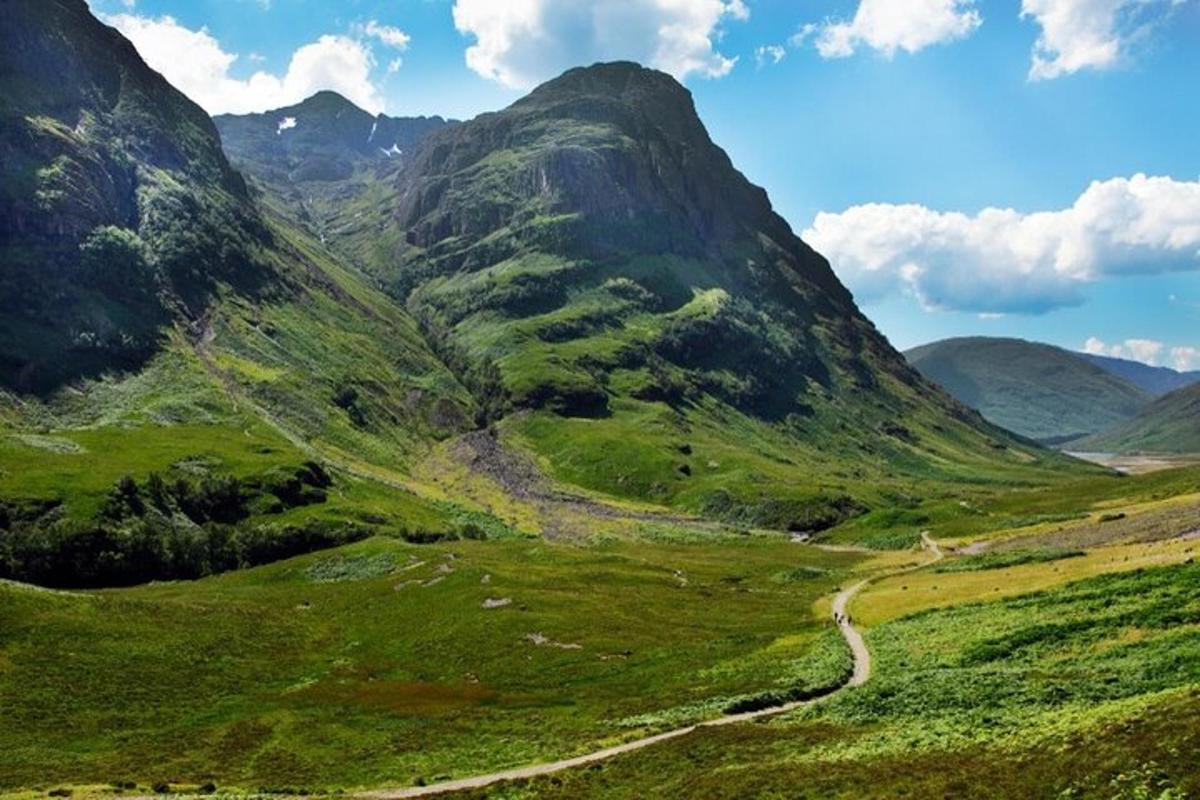 una valle verde con una strada sterrata in montagna