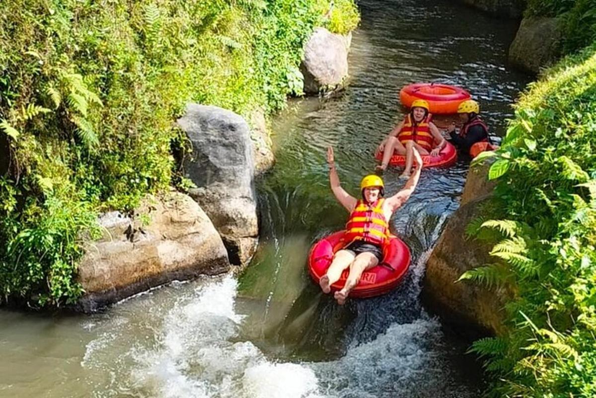 tři lidé sjíždějí řeku na raftu