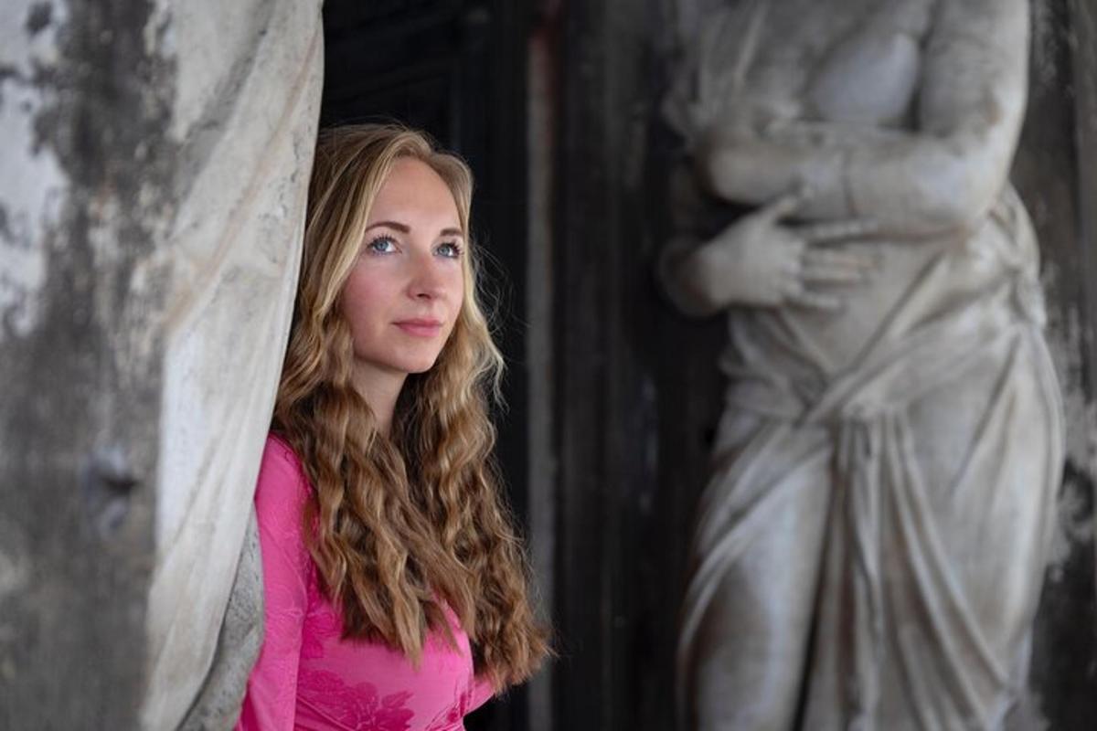 una giovane donna in piedi accanto a una statua