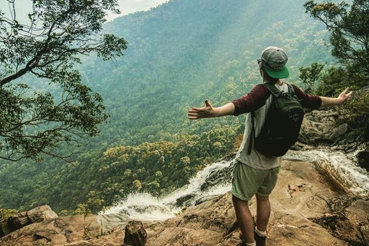 un bărbat care stă pe vârful unui munte și are vedere la o cascadă