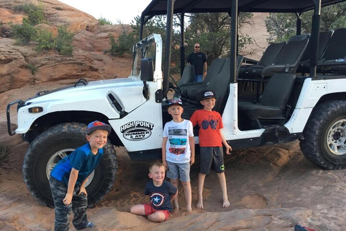 a group of children standing in front of a jeep