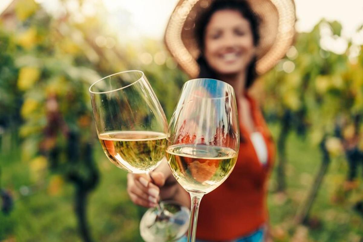 a woman holding two glasses of white wine