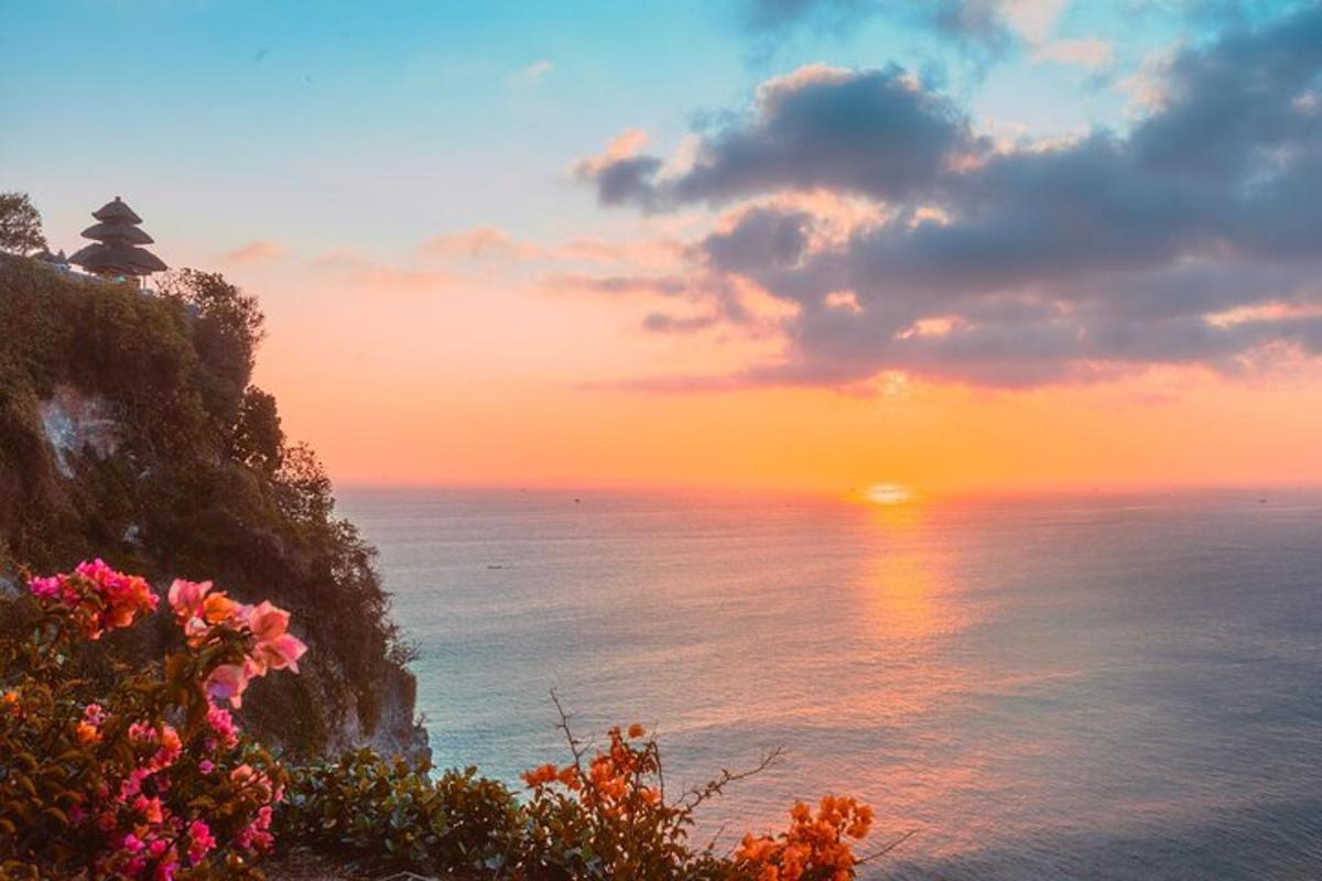 un tramonto sull'oceano con un faro su una scogliera