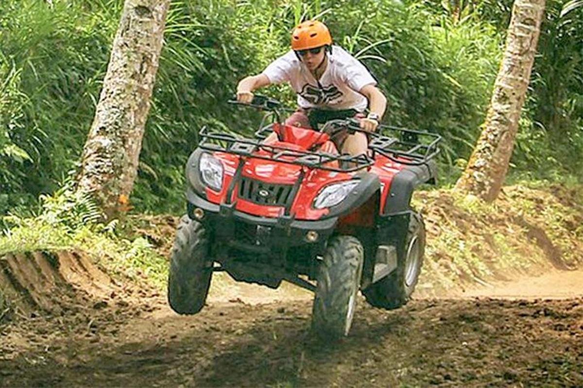 un uomo in sella a un quad su un sentiero sterrato