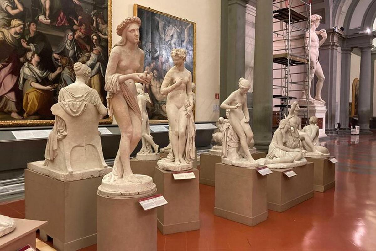 Un grupo de estatuas en un museo con una pintura.