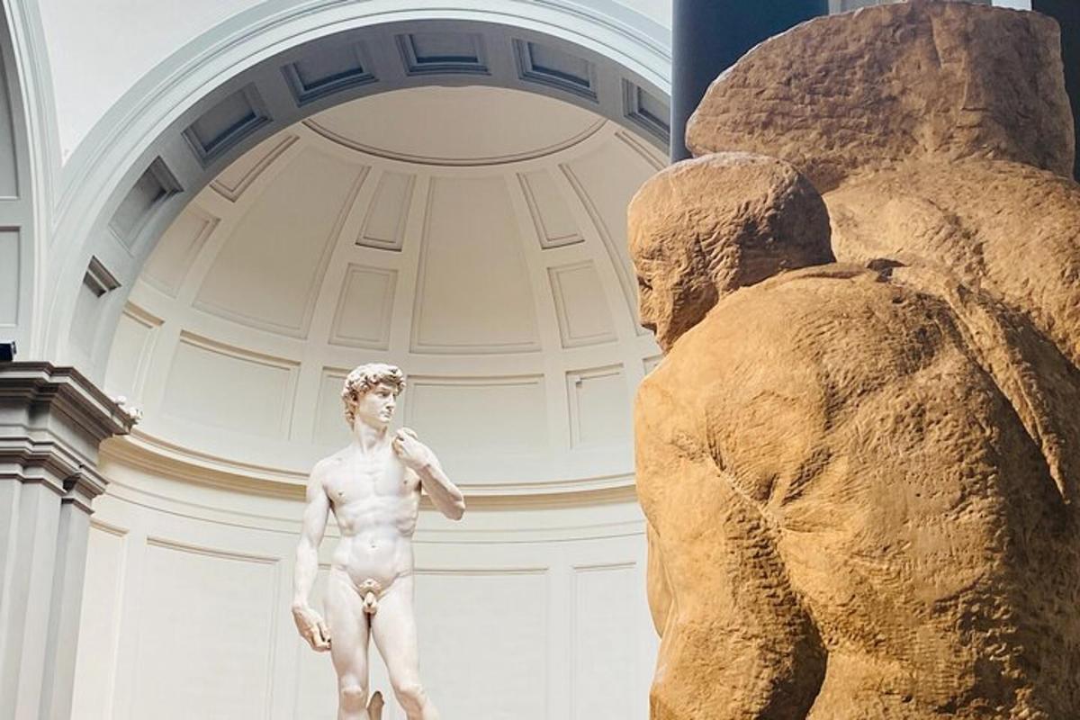 Una estatua de un hombre de pie junto a un oso de peluche gigante.