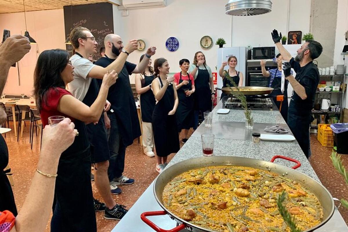 a group of people standing around a table with a pan of food