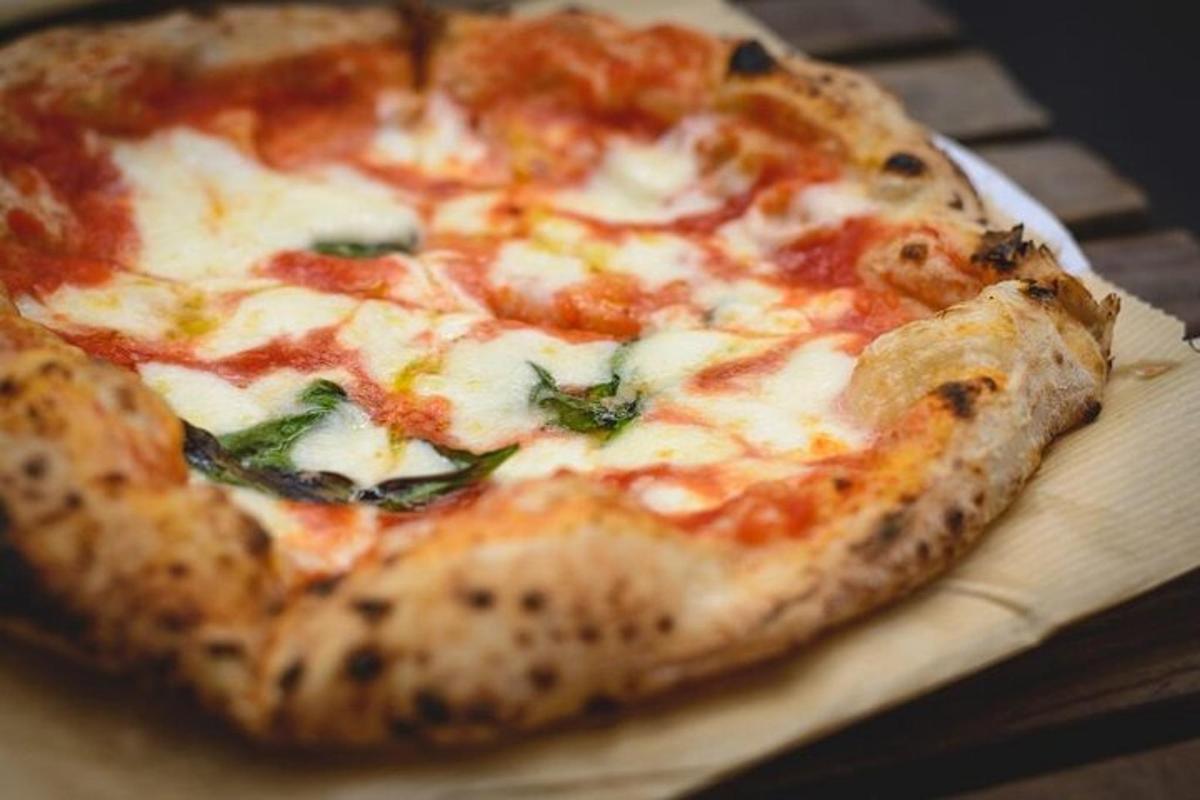 Una pizza colocada encima de una tabla de cortar de madera.