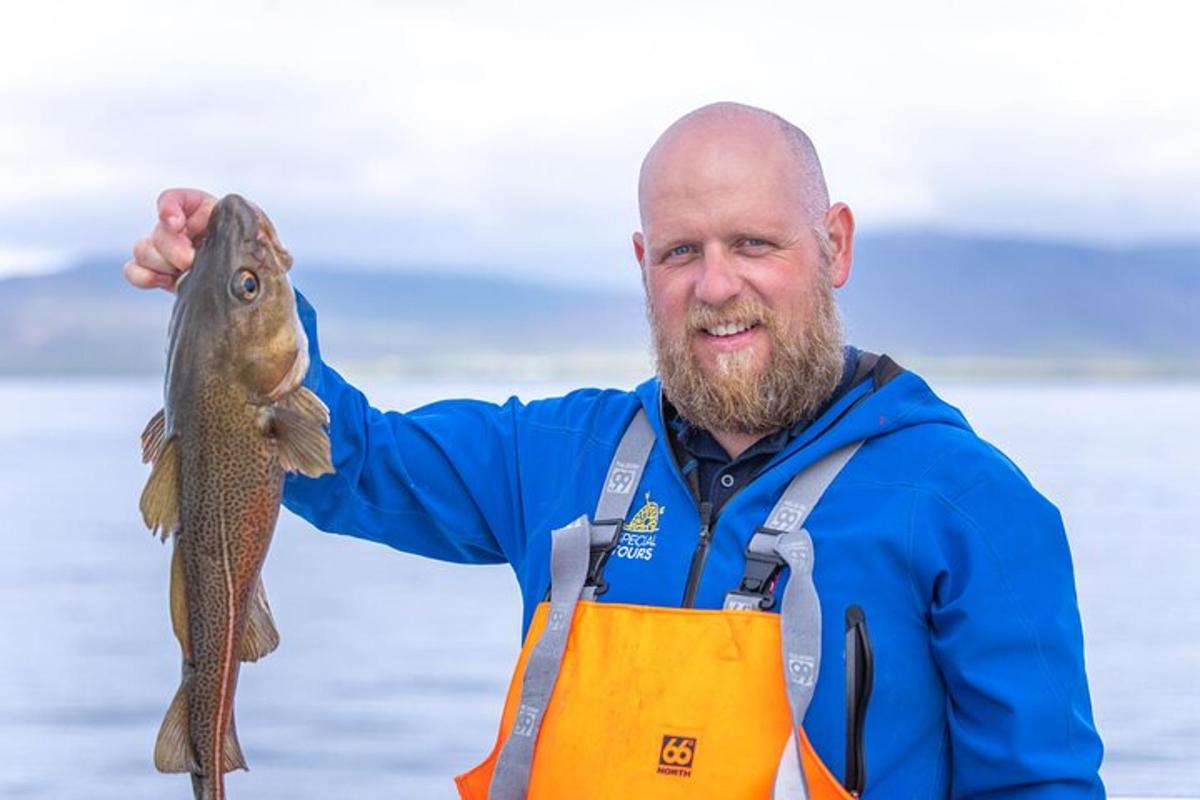 en mann i et forkle som holder opp en fisk