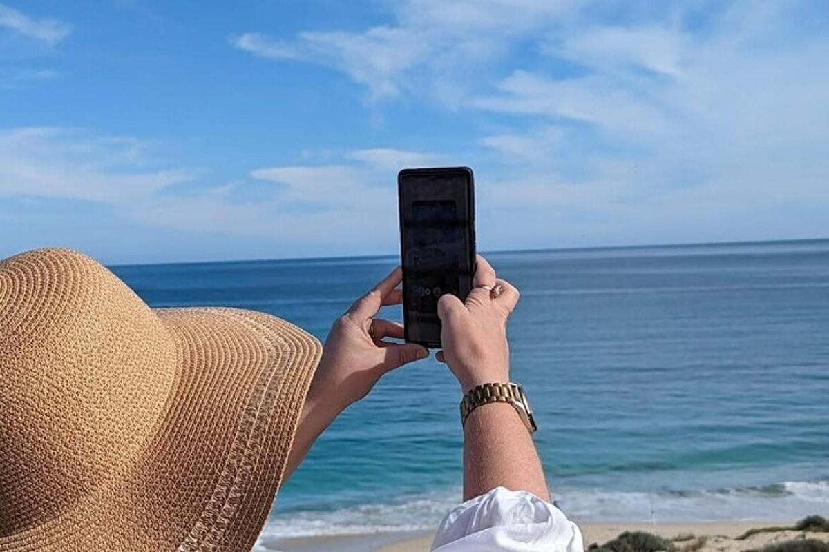 oseba, ki fotografira ocean z mobilnim telefonom