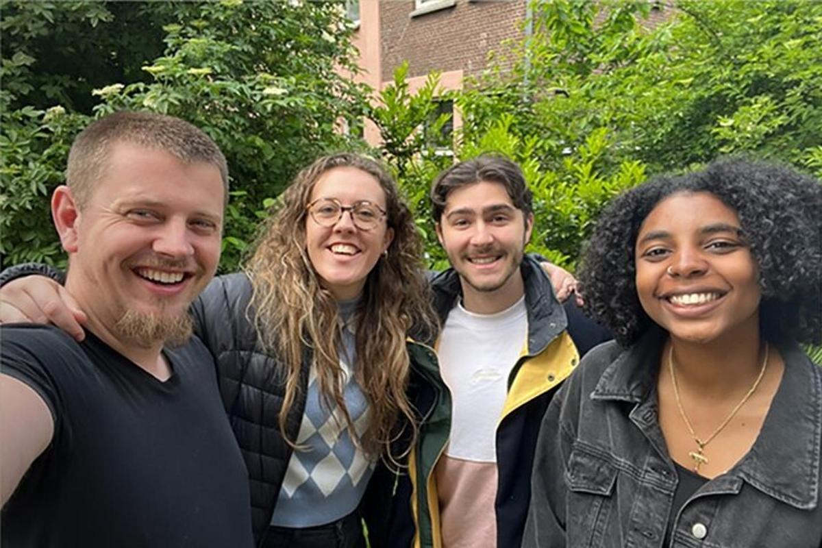 eine Gruppe von vier Personen, die für ein Foto posieren
