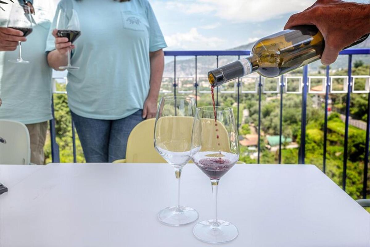 eine Person gießt Wein in zwei Weingläser auf einem Tisch