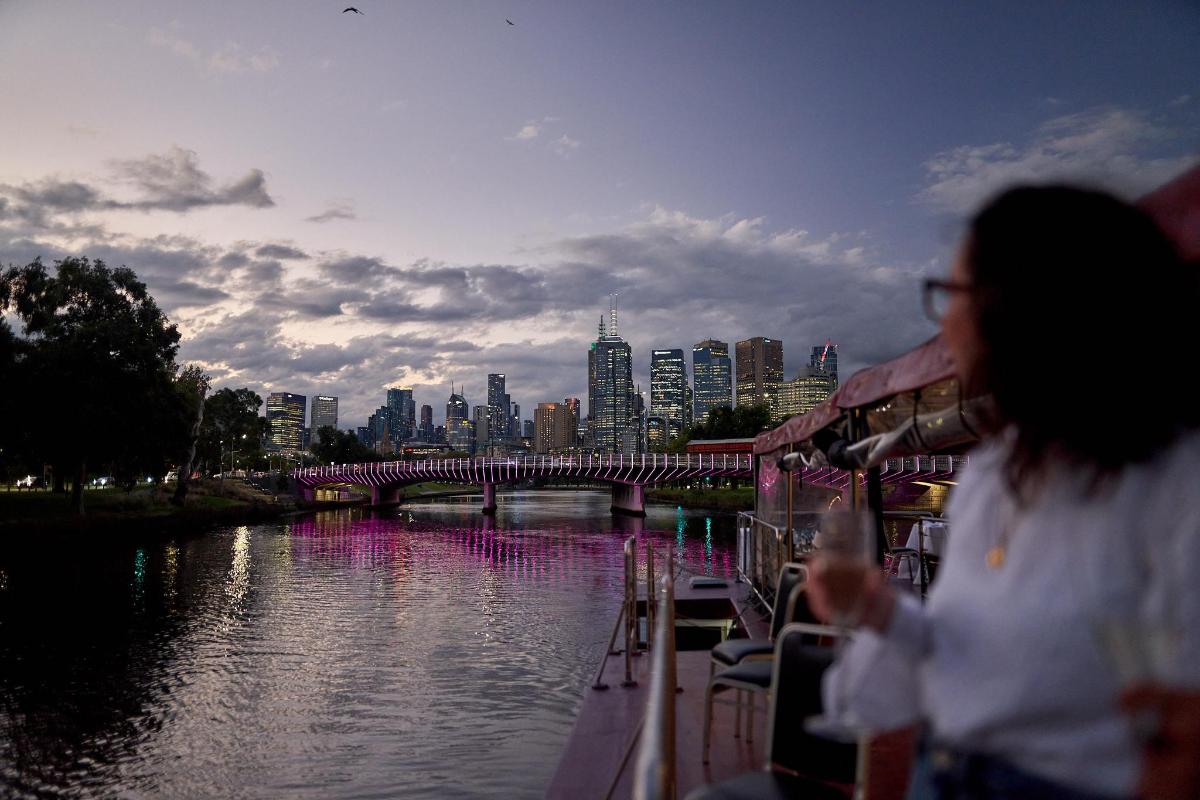a woman is drinking from a boat on a river