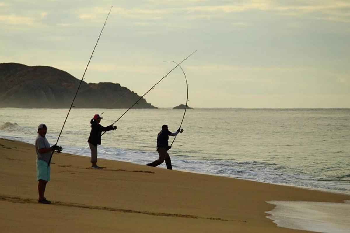 un grup de tres persones pescant a la platja