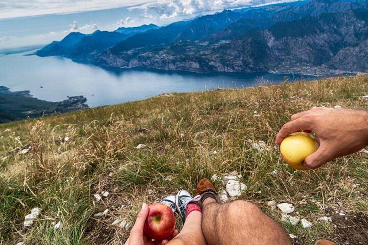 osoba sediaca na vrchole hory a držiaca jablko