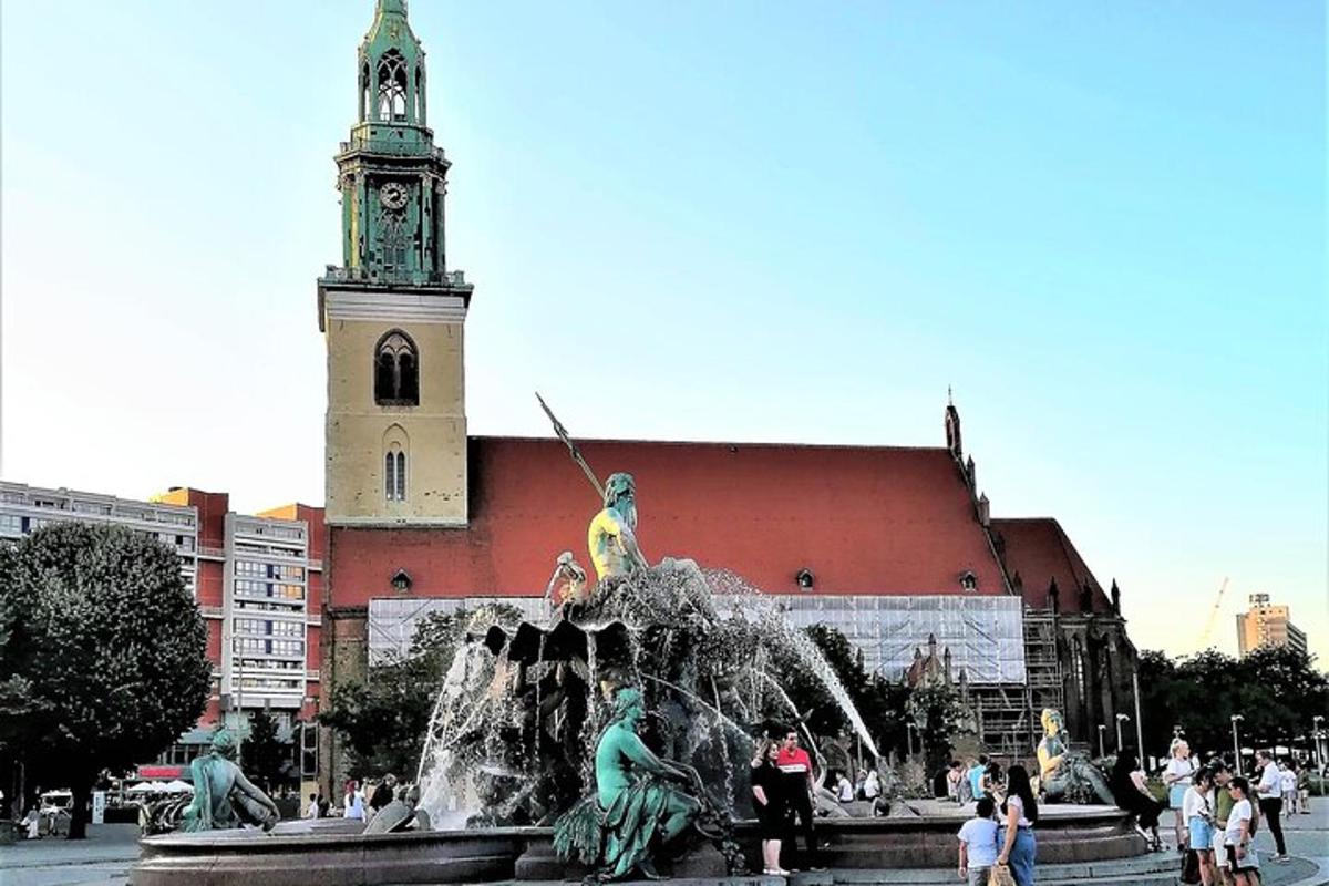 uma fonte com estátuas em frente a um edifício com uma torre do relógio