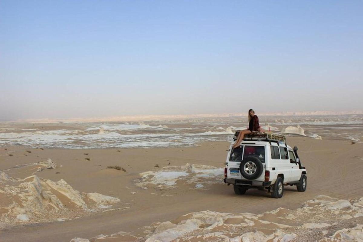 en person som sitter på toppen av en hvit jeep på en strand