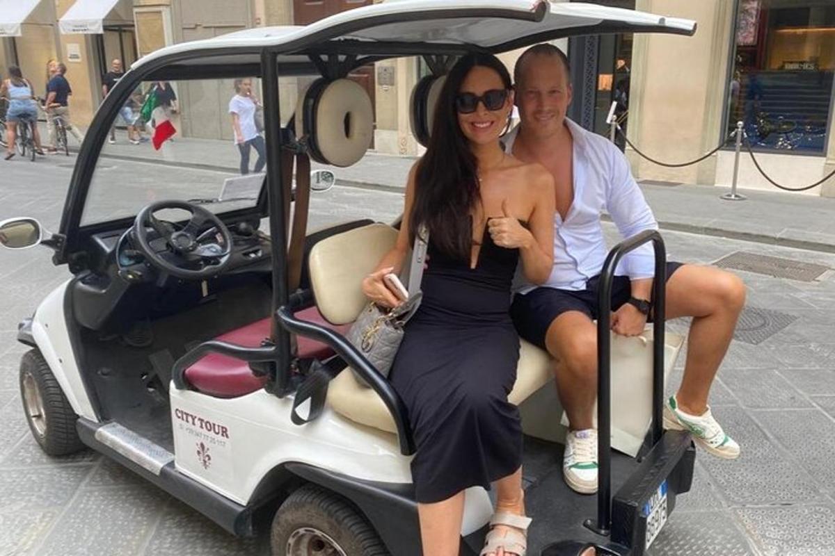 um homem e uma mulher sentados em um carrinho de golfe