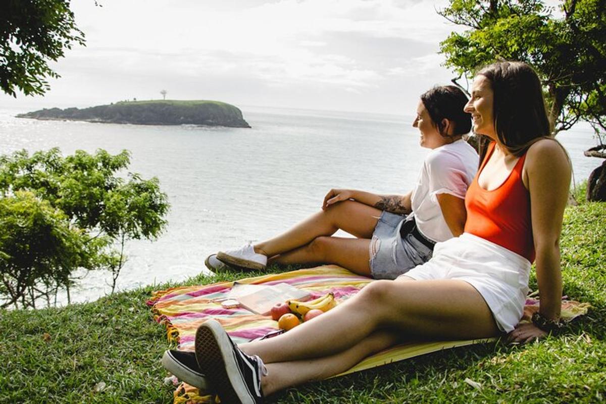 Dos mujeres sentadas en una manta junto al océano.
