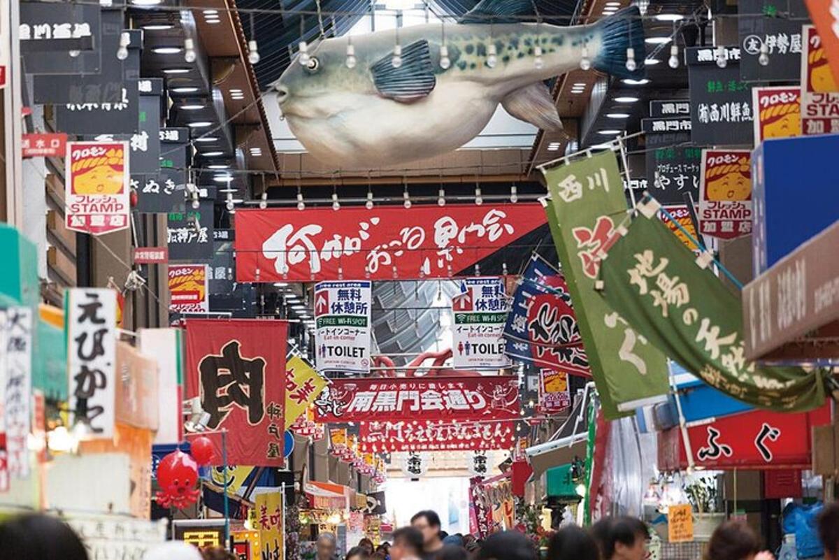 a crowd of people walking through a market with signs