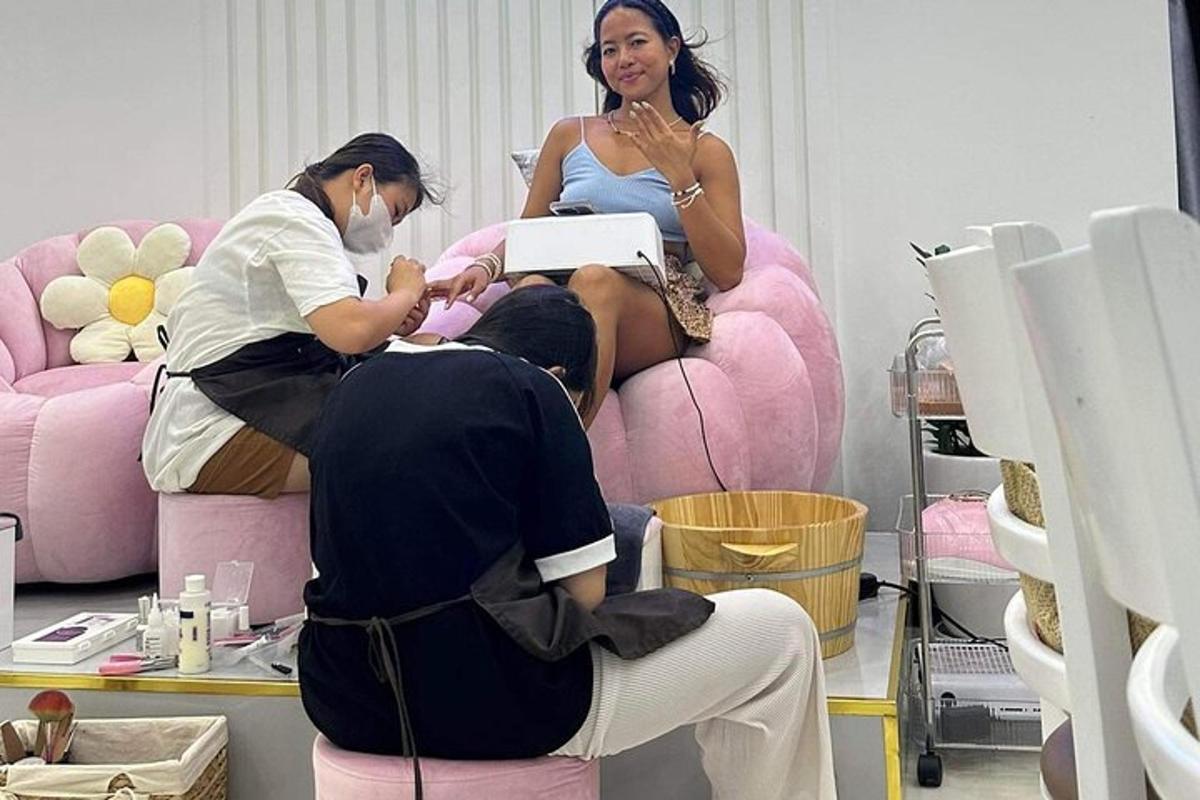 două femei într-un salon cu un bărbat așezat pe un scaun roz