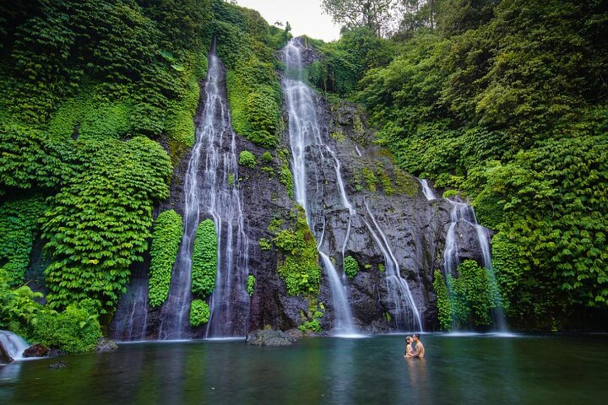 dua orang di dalam air di hadapan air terjun