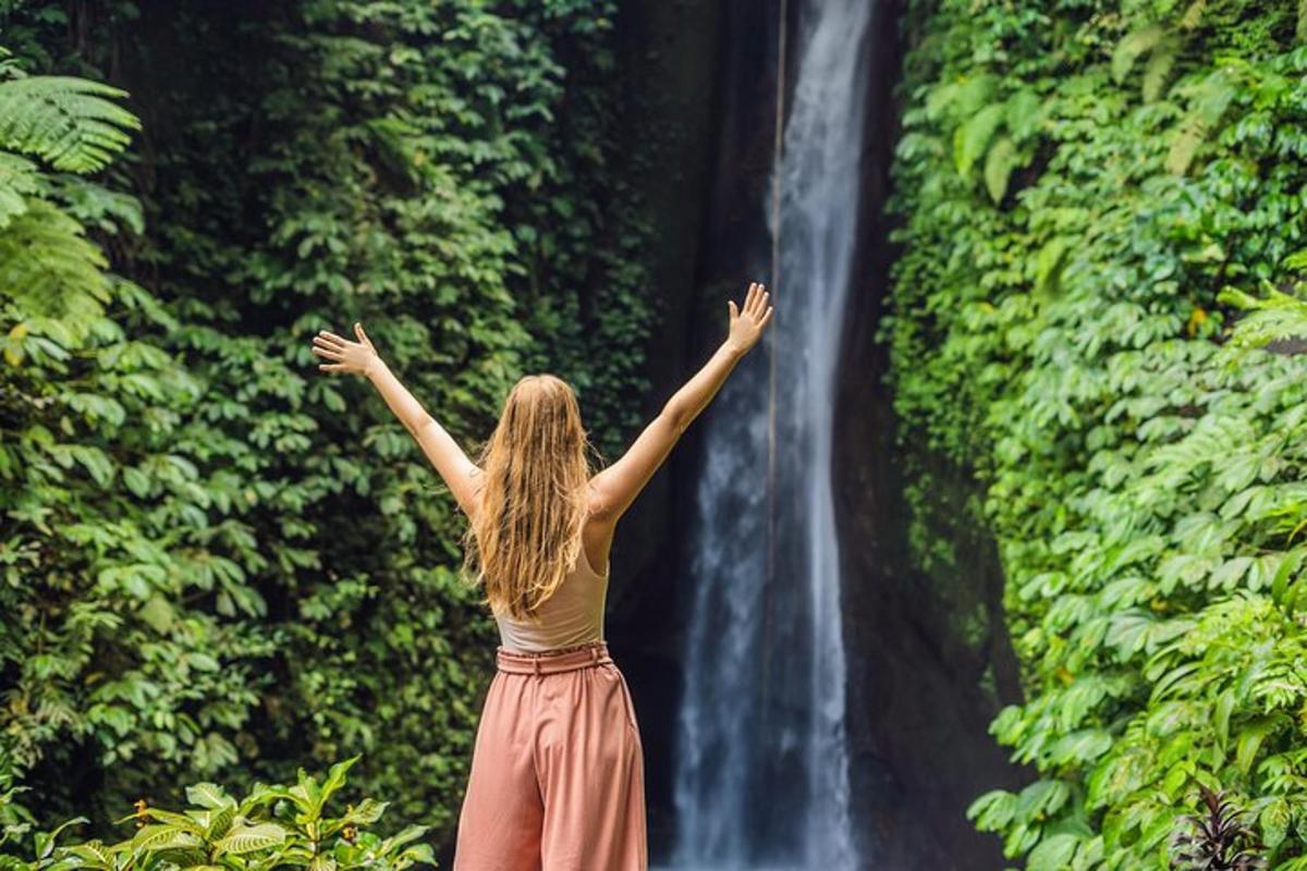 seorang wanita berdiri di hadapan air terjun
