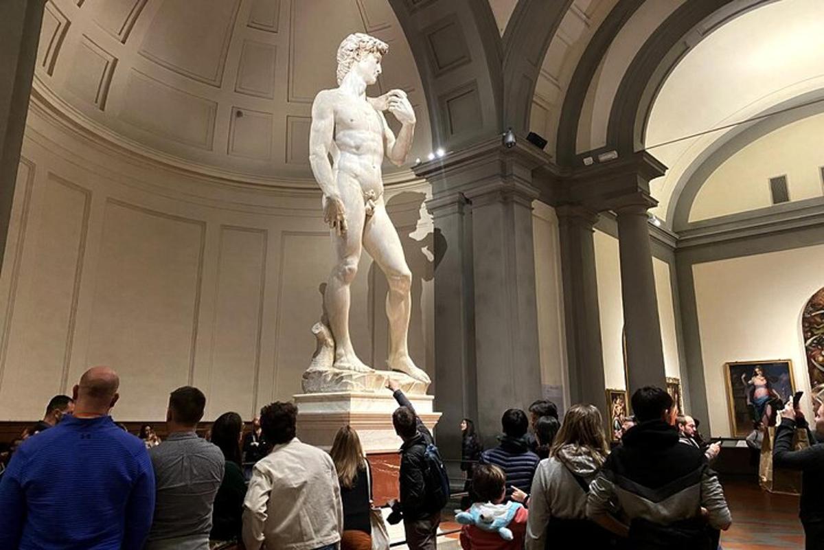 una folla di persone che guarda una statua in un museo