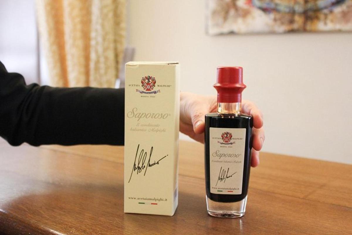 una persona tiene in mano una bottiglia di sapone su un tavolo