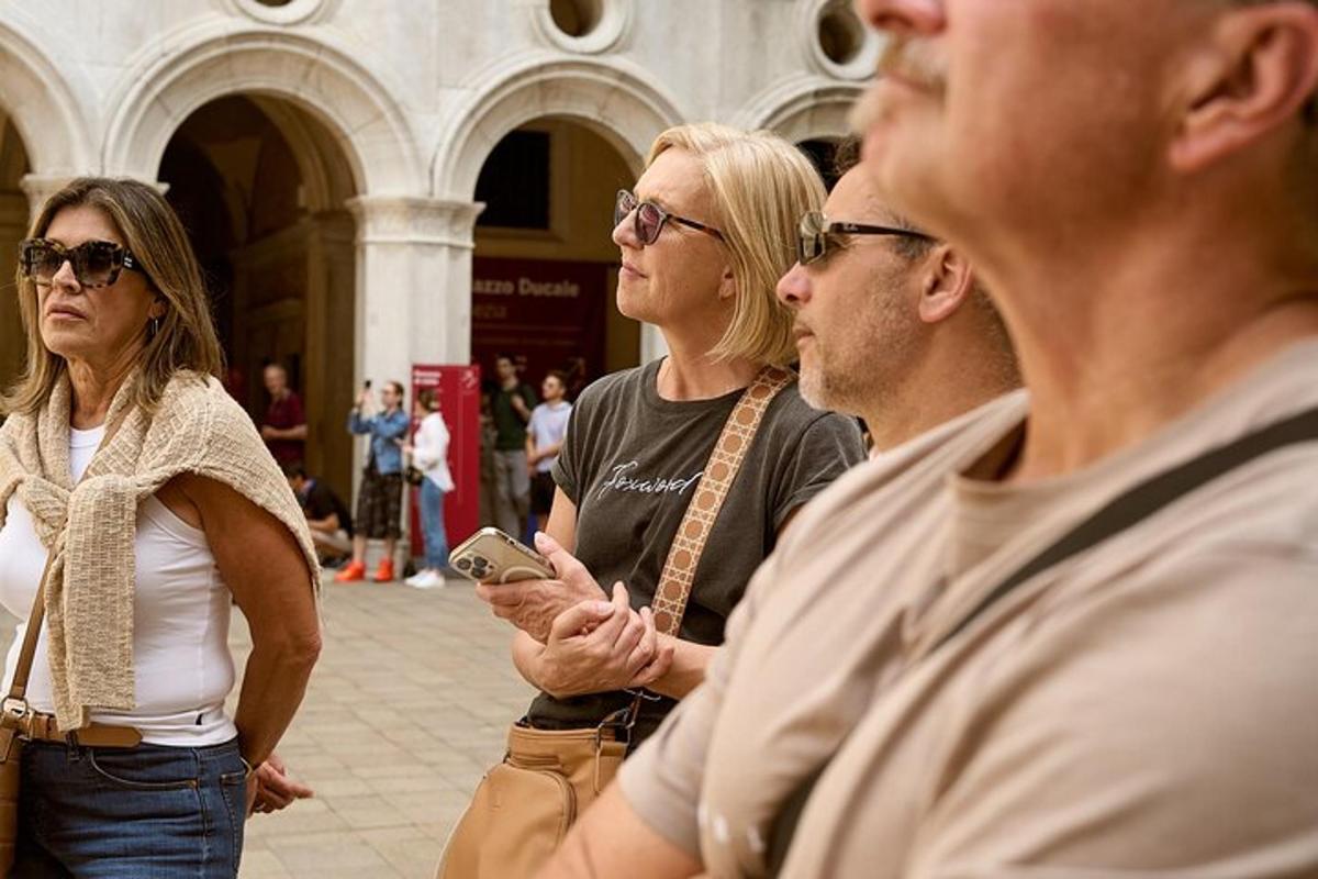 skupina ľudí stojacich pred budovou a pozerajúcich sa do mobilného telefónu