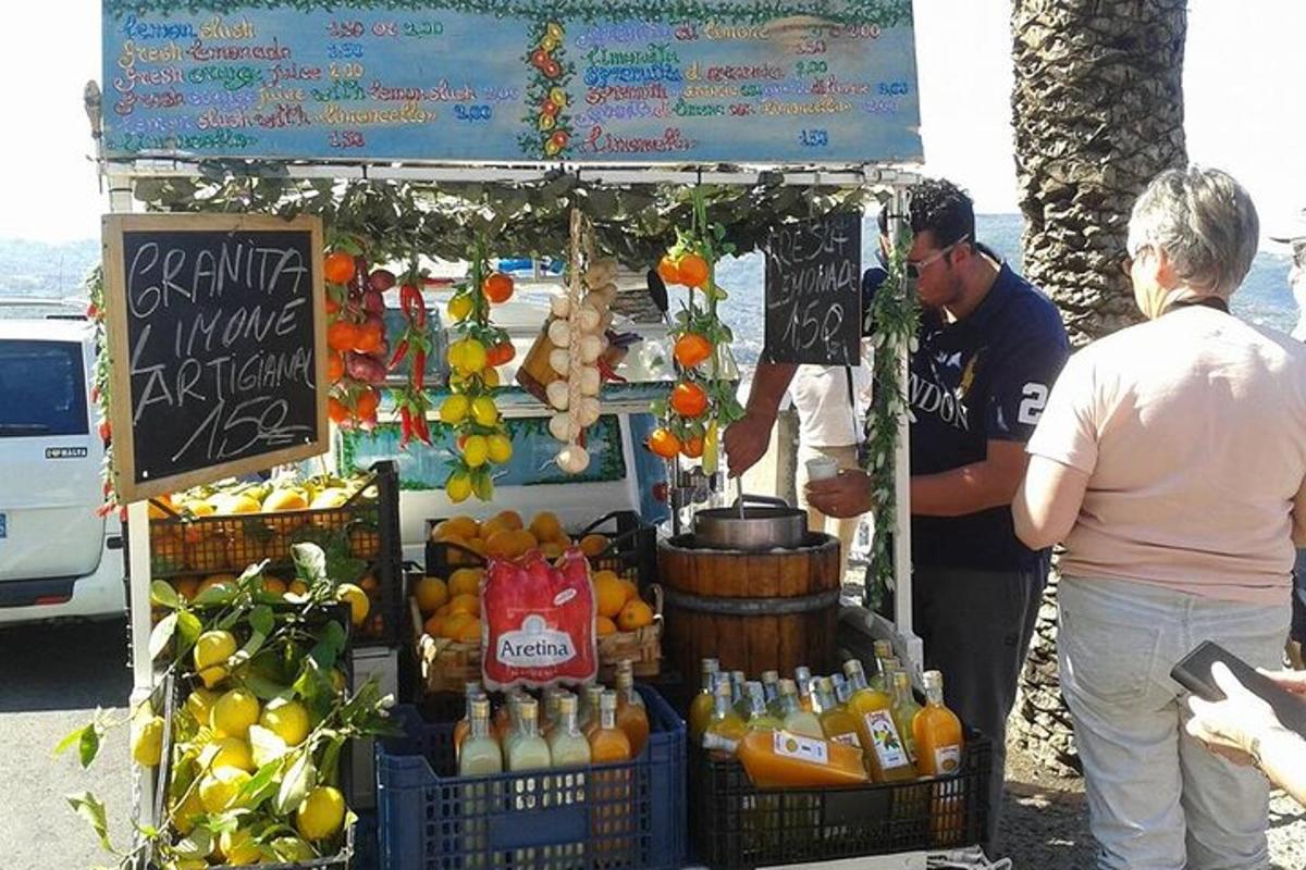 un bărbat care stă în fața unei tarabe cu fructe și sucuri