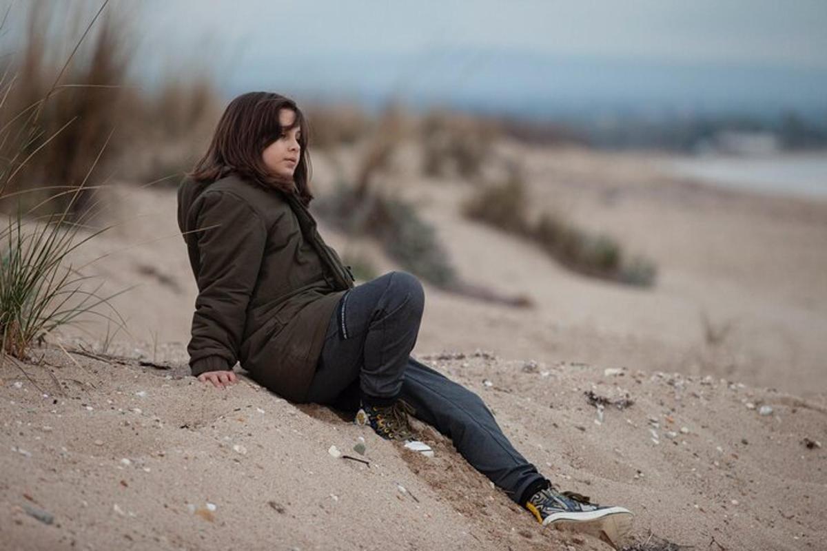 una mujer sentada en la arena de la playa