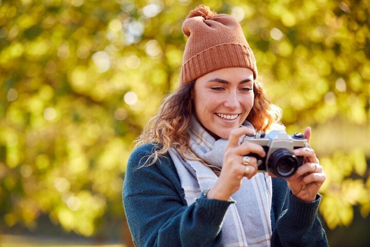 ženska v klobuku, ki fotografira s fotoaparatom