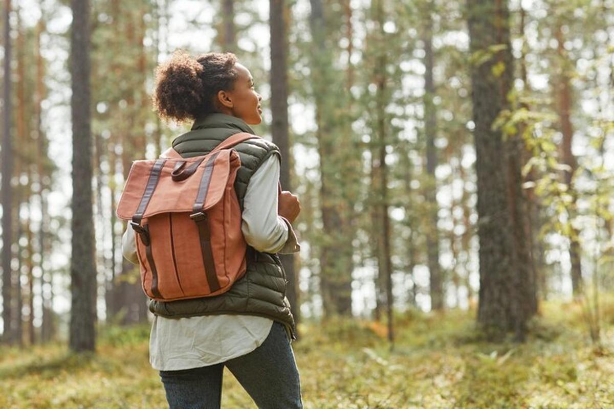 seorang wanita dengan beg galas berjalan melalui hutan