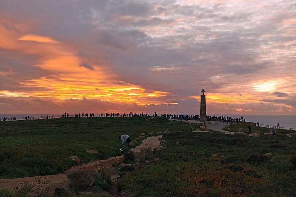 Un grupo de personas de pie alrededor de un faro al atardecer.