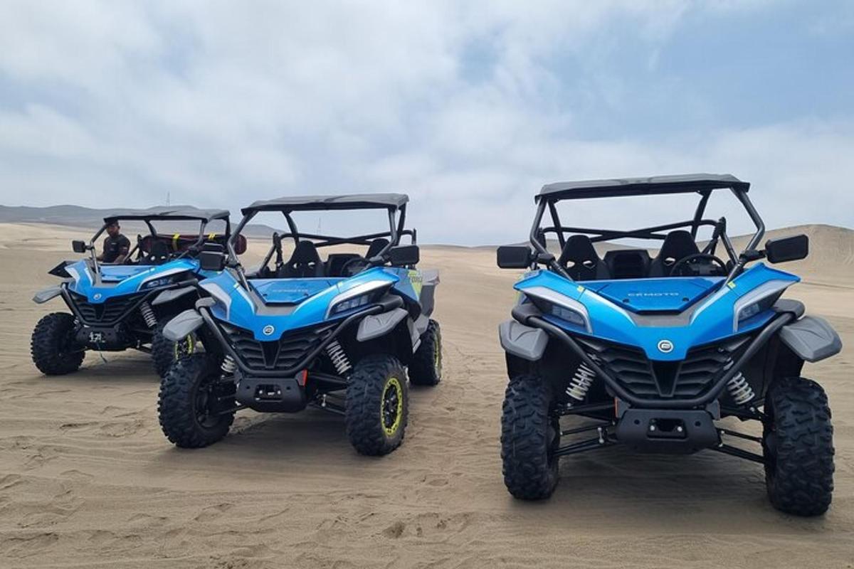 zwei blaue Geländefahrzeuge im Sand geparkt