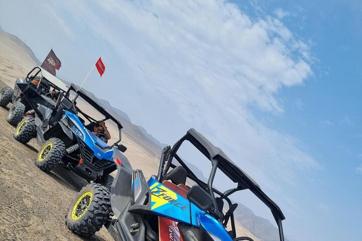 zwei Geländefahrzeuge am Strand neben einem Auto geparkt