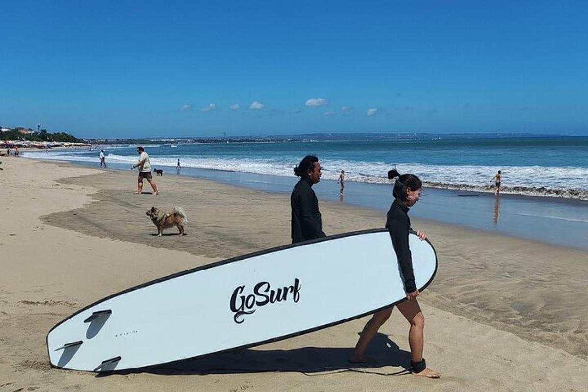 dos personas caminando por la playa con una tabla de surf