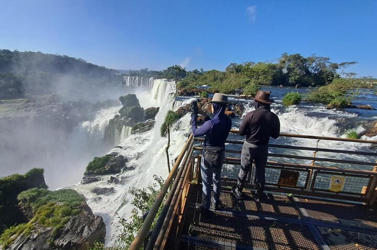 Dos hombres de pie en una plataforma de observación mirando una cascada