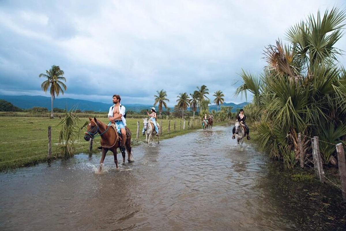 洪水で水浸しになった野原を馬に乗って走る人々のグループ
