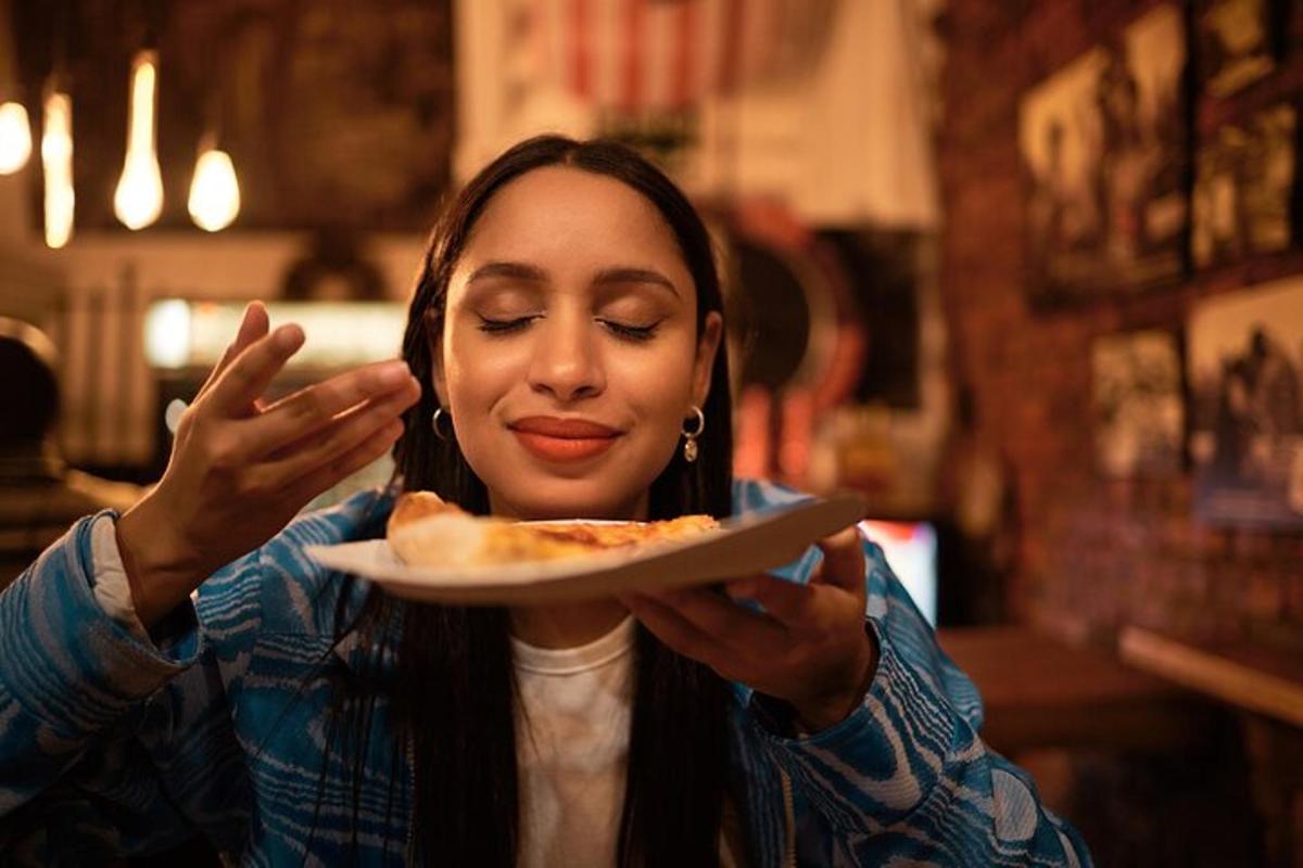 una donna che mangia una fetta di pizza su un piatto