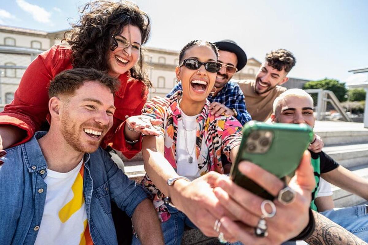 eine Gruppe von Menschen, die lachend auf ein Mobiltelefon schauen