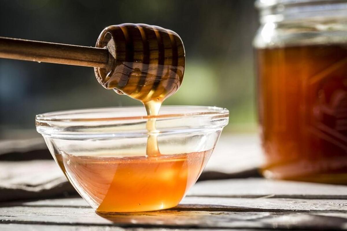 a honey spoon pouring honey into a bowl of honey