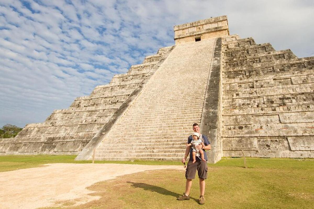 muž držící dítě před pyramidou
