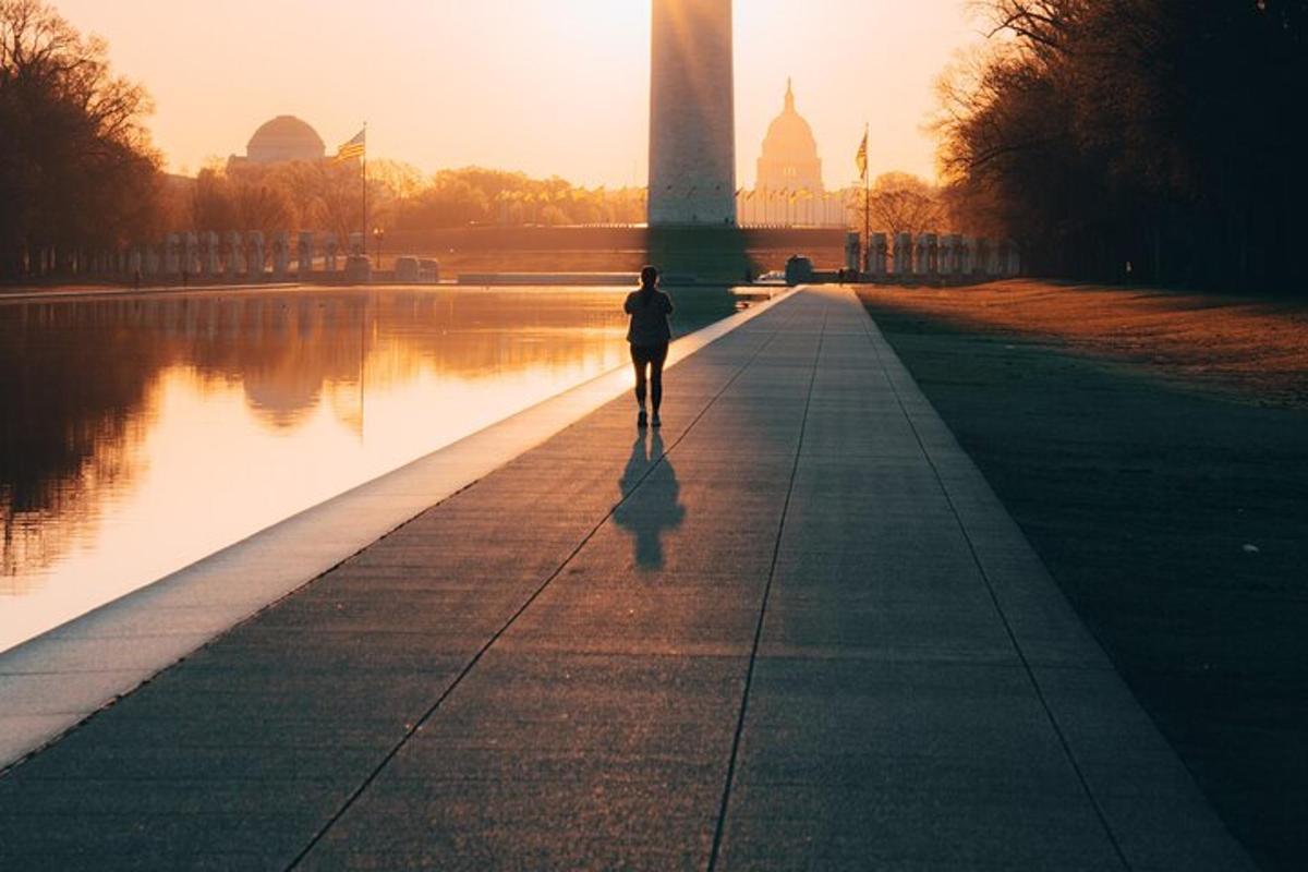 osoba kráčející po chodníku před Washingtonským monumentem